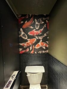 Image of toilet with koi fish wall paper above it.